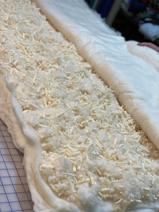 Cross-section of Wool and Latex Topper by Sleep & Beyond - 3 inch thickness revealing natural latex shreds and wool filling for pressure relief.